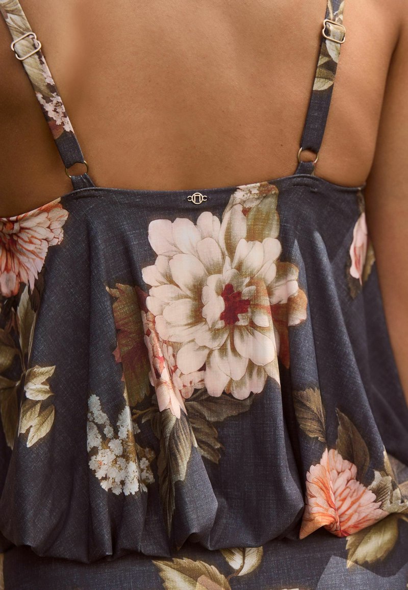 Top a stampa floreale in blu scuro con texture plissettata, spalline regolabili e dettagli floreali in rosa e verde. Include dettagli in metallo dorato.