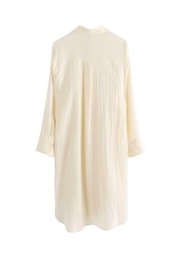 Camicia a maniche lunghe di colore crema chiaro, realizzata in tessuto testurizzato, con polsini con bottone e colletto classico. Vista posteriore mostrata.