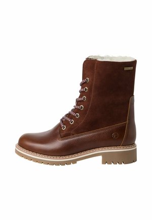Bottines montantes en cuir marron et daim avec une doublure en fourrure douce, semelle en caoutchouc et lacets à motifs. Détail du logo sur le côté.
