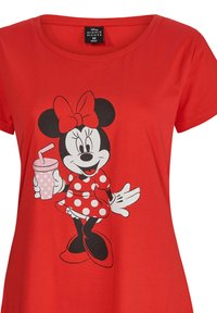 Camiseta corta de mangas rojas con un gráfico de Minnie Mouse en blanco y negro, vestida con un vestido de lunares y sosteniendo una bebida rosa con una pajita.