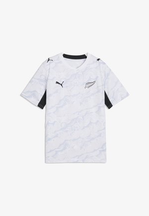 Maglia sportiva bianca con motivo a vortice sottile, loghi Puma neri sul petto e sulle spalle, ed emblema di felce nero sulla parte anteriore.