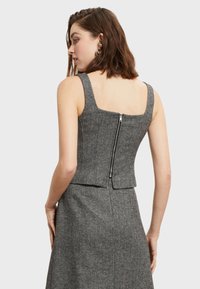 Grijze herringbone-patroon mouwloze top met een vierkante halslijn en een ritsdetail op de rug. Gelaagd stof met een getailleerde silhouet.