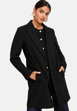 Manteau en mélange de laine noir avec un col à revers, des boutons devant et des poches latérales. Présente une coupe ajustée et une texture lisse.