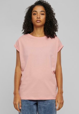 T-shirt surdimensionné rose clair avec des manches courtes roulées ; en coton doux ; encolure ronde ; coupe décontractée ; texture lisse.