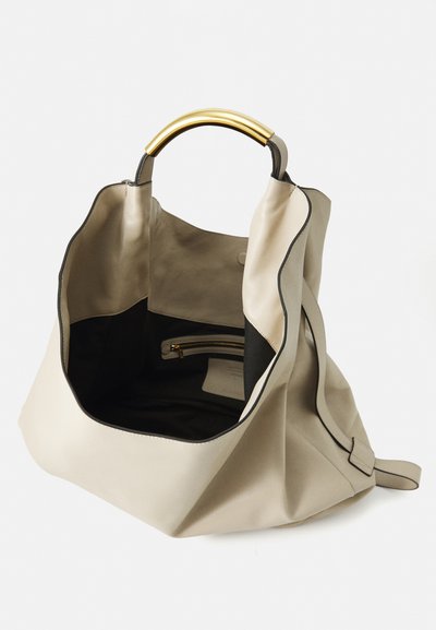 Sac à main en cuir beige avec une poignée en métal doré structuré, ouverture supérieure montrant un intérieur noir et une petite poche zippée à l'intérieur.