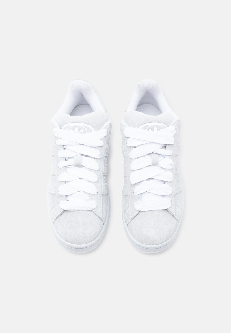 Weiße Wildledersneaker mit flachen weißen Schnürsenkeln, abgerundetem Zehenbereich und cremeweißer Gummisohle. Logo auf Zunge und Seite geprägt.