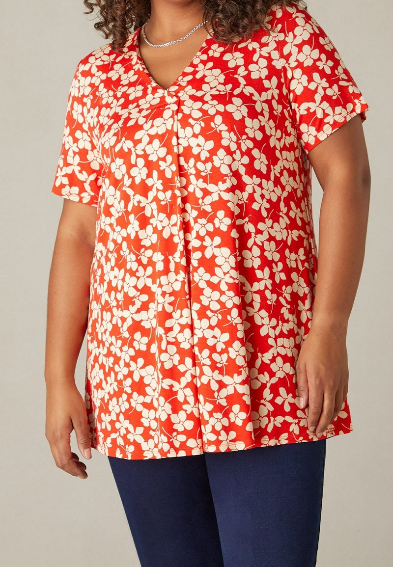 Blusa roja de manga corta con escote en V, con un patrón floral blanco. Tela suave y ligera con un corte holgado y detalle de plisado en la parte delantera.