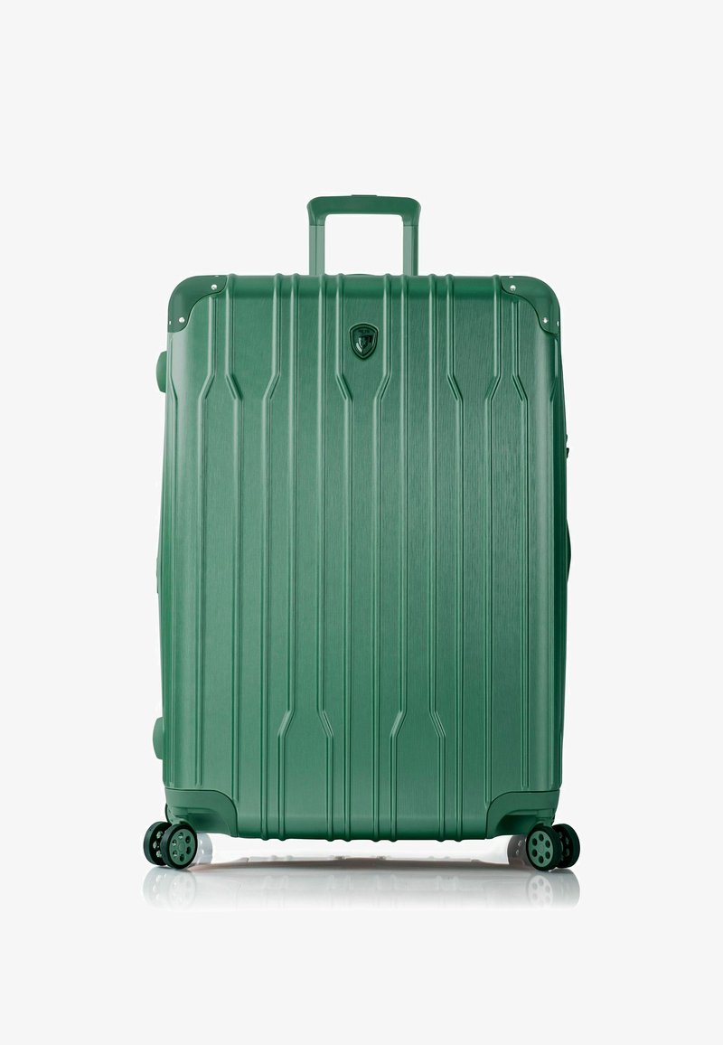 Valigia rigida verde con scanalature verticali, manico retrattile, quattro ruote multidirezionali e un logo sulla parte anteriore.
