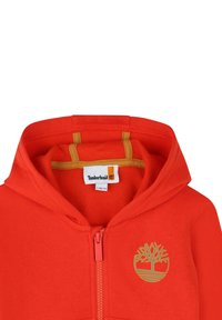 Felpa rossa con zip realizzata in misto cotone, con un logo dorato a forma di albero sul lato sinistro del petto, un interno morbido e dettagli gialli a contrasto.