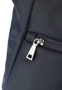 Borsa in tessuto blu navy con zip metallica e un tasca quadrata. La superficie presenta un motivo testurizzato con dettagli di cucitura visibili.