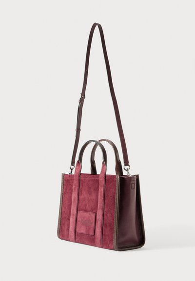 Kis téglalap alakú bordó velúr és bőr kézitáska dupla fogantyúkkal és állítható hosszú vállpánttal, fehér háttérrel.