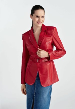 Czerwony skórzany blezer o dopasowanej sylwetce, z pojedynczym zapięciem na guzik, paskiem w talii i długimi rękawami, zestawiony z dżinsową spódnicą.
