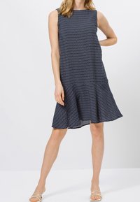 Ärmelloses marinblaues Kleid mit weißem geometrischen Muster, fließender A-Linienform und ausgestellt geschnittenem Saum. Hergestellt aus leichtem Stoff, knöchellang.