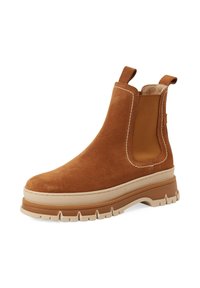 Hnědé semišové Chelsea boty s béžovou robustní gumovou podrážkou, elastickými bočními panely, poutky na přední a zadní straně a bílým šitím.