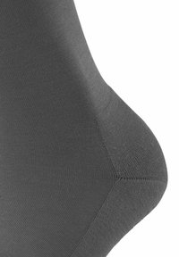 Calzino grigio caratterizzato da una texture liscia e elastica con una forma affusolata. Cuciture evidenti e motivo a costine lungo il corpo. Dettagli di design minimal.