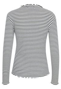 Hosszú ujjú, fekete-fehér csíkos felső, bordázott textúrával, fodros nyakkivágással és szegéllyel. Az alakhoz illeszkedő fazon kiemeli a test vonalait.