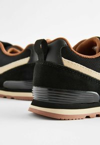 Czarno-brązowe sneakersy z zamszowej i siateczkowej góry, zaokrąglonym noskiem, teksturowanym czarnym obcasem oraz beżową gumową podeszwą z bieżnikami.