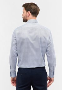 Camicia a maniche lunghe di colore azzurro chiaro con motivi geometrici. Design con colletto, polsini con bottone e tessuto di cotone liscio. Vista posteriore mostrata.