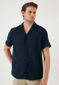 Donkerblauw korte mouwen overhemd met knopen en een camp collar, gladde stof en subtiele textuur, met een rechte zoom en gestikte details.