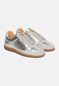 Silver metallic leather sneakers with a gum rubber outsole, padded tongue, and soft beige lining. Features gray laces and subtle branding.