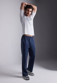 Lichtgrijze sportshirt, marineblauwe broek met witte strepen en metalen sneakers. Katoenmengsel, relaxte pasvorm en textuurdesign.