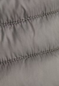 Gray puffer fabric with a smooth texture, featuring horizontal seams and contrasting stitching. The surface appears slightly shiny.