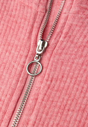 Tessuto rosa a coste con una cerniera metallica argentata. La cerniera presenta una linguetta circolare e dettagli intricati sui denti.