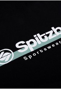 Black fabric sportswear with a large white logo saying "Spitzb" and a light teal stripe underneath. Soft texture, casual design.