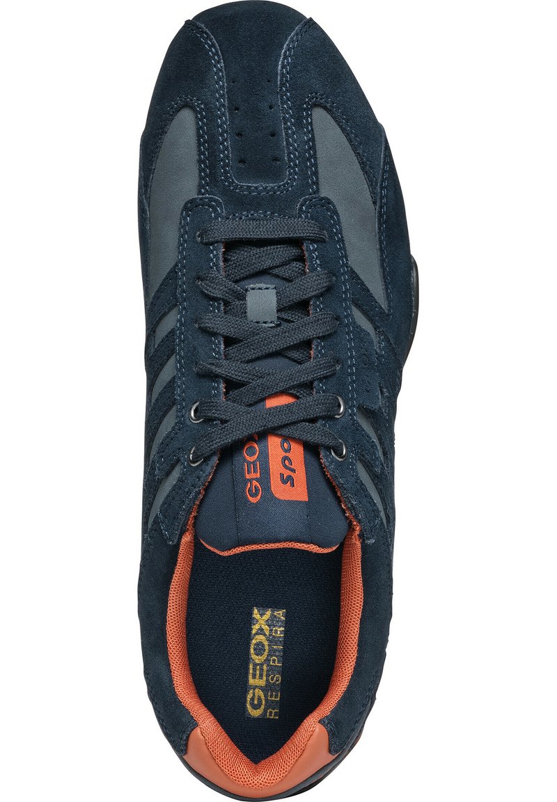 Zapatilla deportiva azul oscuro con materiales de ante y malla, con acentos en naranja, seis ojetes y lengüeta acolchada. Logo notable en la plantilla.