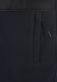 Chaqueta de forro polar navy con un panel negro suave en la parte superior, que incluye un bolsillo con cremallera y una tela texturizada para mayor calidez.