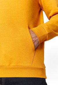 Lysegul sweatshirt med en tekstureret finish, der har en kængurulomme og ribstrikkede manchetter ved ærmerne og nederste kant.