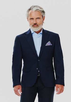 Navy blue marynarka ze dwoma guzikami, kieszeniami z klapkami oraz wzorzystą poszetką. Jasnoniebieska koszula pod spodem. Gładka faktura materiału.