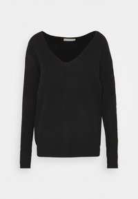 Svart stickad tröja med V-ringning, långa ärmar och avslappnad passform. Texturerad tyg med subtila ribbdetaljer genom hela plagget.