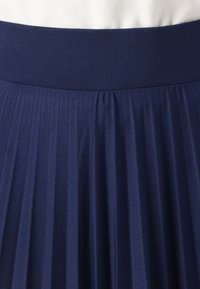 Námořnická plisovaná sukně s širokým elastickým pasem. Vyrobena z lehkého materiálu, s hladkou texturou a vertikálním plisováním.