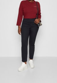 Burgundy långärmad skjorta i kombination med högmidjade svarta byxor och vita platåskor. Enkel design med minimal detaljer.