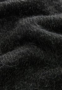 Tessuto di lana grigio scuro con un motivo di lavorazione a maglia testurizzato. Aspetto morbido con fibre chiare visibili distribuite uniformemente.