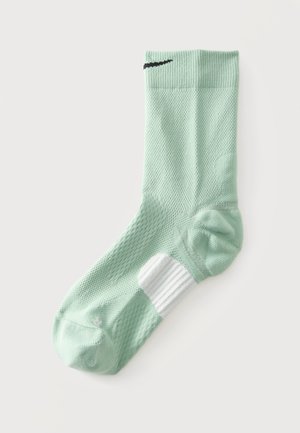Hellgrüne Sportsocke mit weißer gepolsterter Sohle und schwarzem Nike-Swoosh nahe dem Bündchen, flach auf weißem Hintergrund dargestellt.