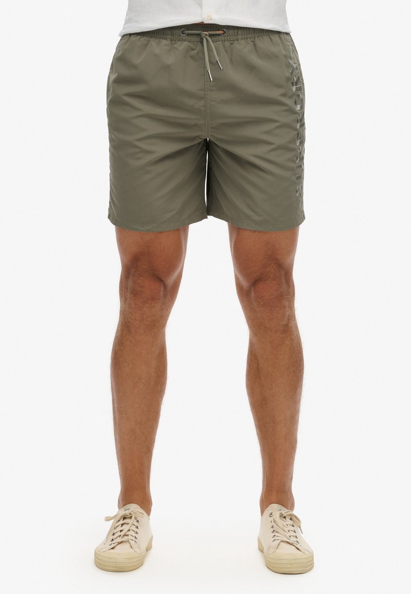Costumi da bagno verde oliva realizzati in tessuto leggero, dotati di una vita elastica con cordoncino e dettaglio del logo laterale.