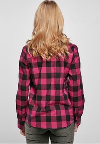 Rosa och svart rutigt flanellskjorta med långa ärmar, knäppning framtill och rundad nederkant, med bakre ok och figursydd silhuett.