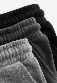 Vier Paare von Sweatpants mit elastischem Bund in verschiedenen Farbtönen: schwarz, dunkelgrau, mittelgrau und meliert grau, die weiche Texturen aufweisen.