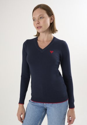 Maglione navy a maglia con scollo a V, ricamo a forma di cuore rosso sul lato sinistro del petto e rifiniture rosse a contrasto ai polsini e all'orlo.