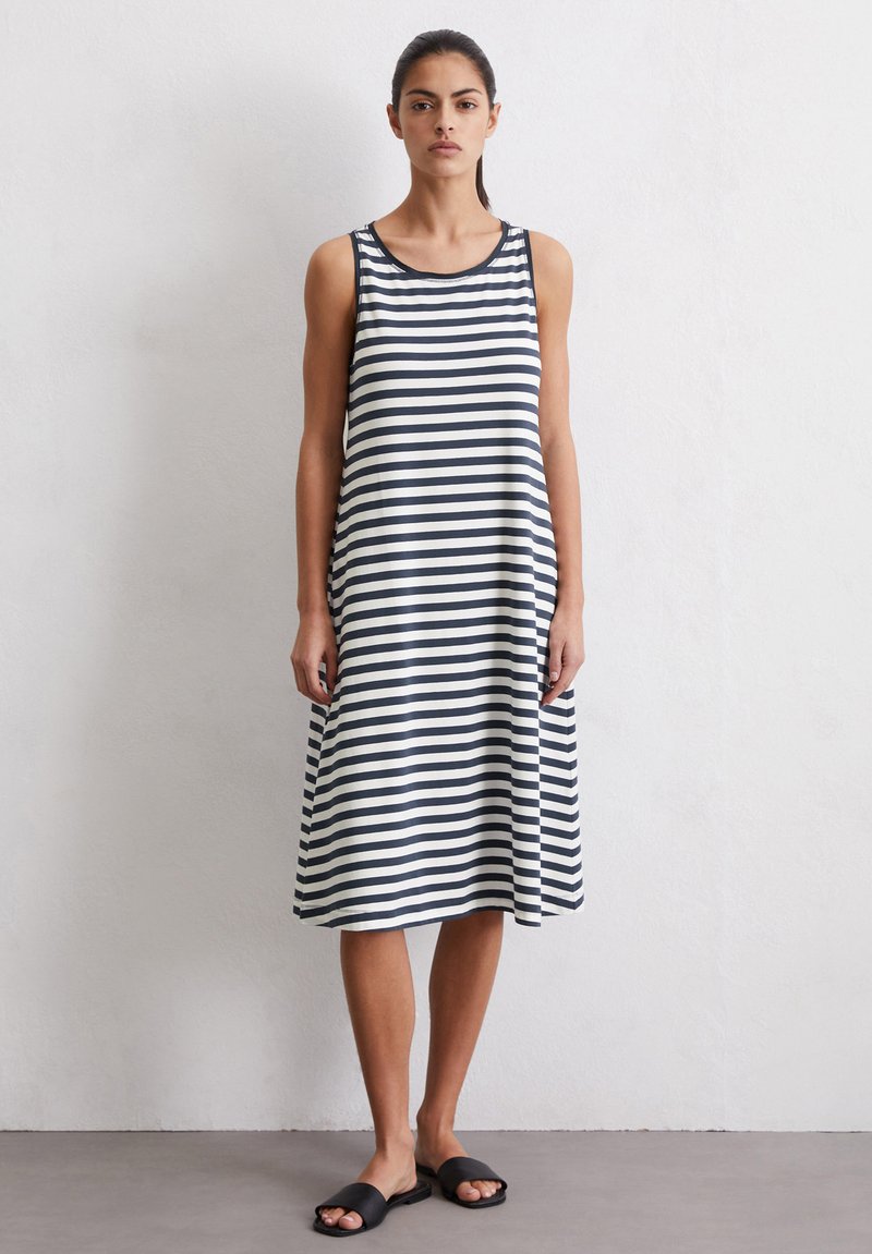 Gestreepte jurk met een mouwloos ontwerp in marineblauw en wit. Kenmerkt zich door een ronde halslijn en een losse silhouette. Draagt met zwarte instapsandalen.