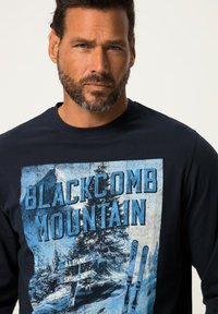 Marineblaues Langarm-T-Shirt mit Grafik "Blackcomb Mountain"; zeigt verschneite Berge, Bäume und Skisymbole in Blau- und Weißtönen.