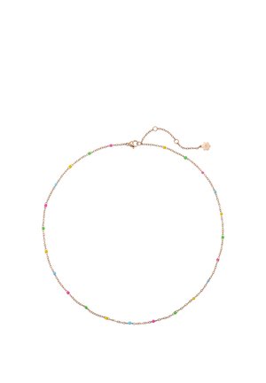 Frau trägt goldene Creolen in Herzform, geschichtete goldene Halsketten mit bunten Perlen und passendes Armband, gekleidet in weißes ärmelloses Oberteil.