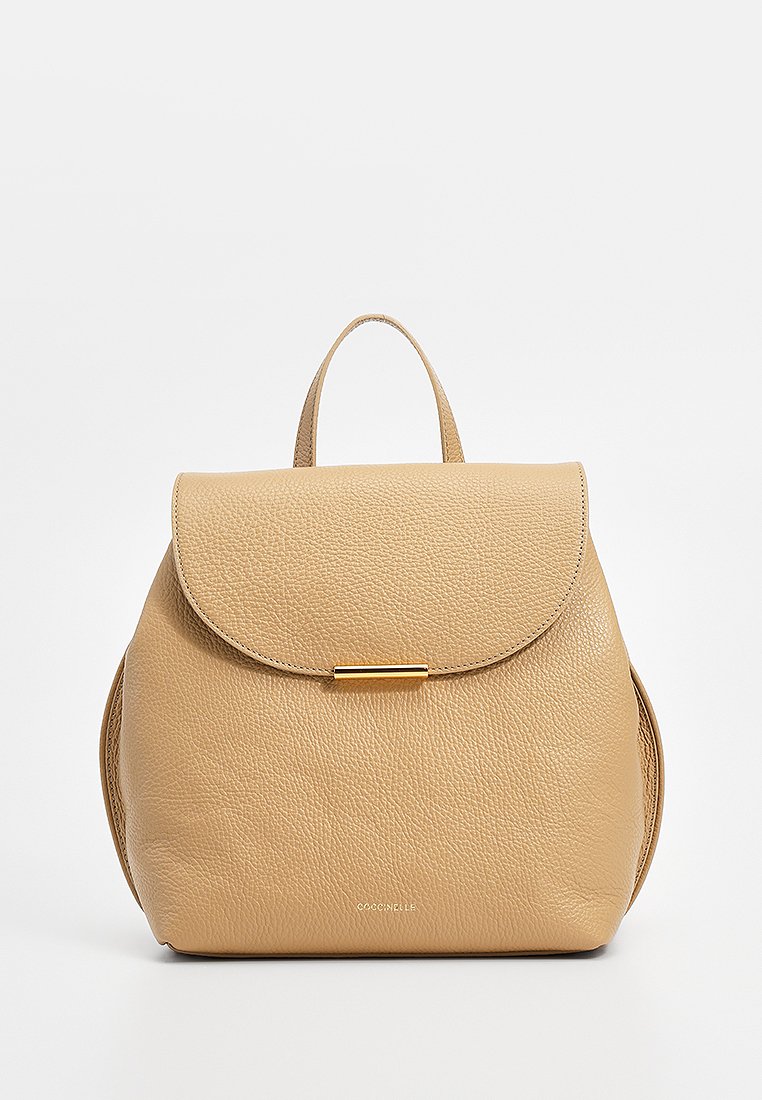Tanfarbene Leder-Rucksack mit abgerundeter Silhouette, Klappenverschluss, goldfarbener Hardware und einem kurzen Griff oben. Texturierte Oberfläche.