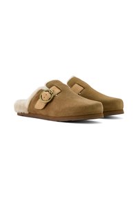 Brown suede slip-on clogs with a soft cream fur lining, featuring a decorative buckle and a flat, textured sole.