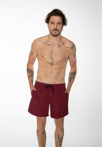 Shorts de bain bordeaux avec cordon noir ; matière légère ; comprend des poches latérales et un petit logo en bas à gauche.