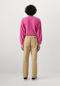 Lyserød oversized sweatshirt med ribbede manchetter, parret med beige, lige ben bukser med elastisk talje og baglomme.