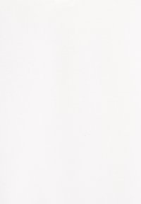 Dos mujeres sentadas en pufs grises en una habitación luminosa, usando portátiles y leyendo un cuaderno, rodeadas de plantas y estanterías.