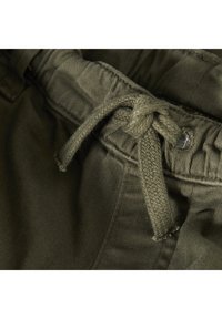 Olivgröna shorts med dragsko i midjan, tillverkade av mjukt bomullstyg. Har en texturerad yta och subtila sömnadsdetaljer.